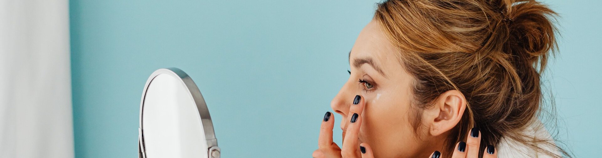 woman checking her skin in the mirror