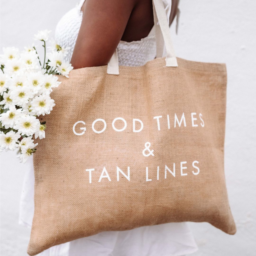 Boracay Skin jute beach tote bag over the shoulder of model holding flowers outdoors