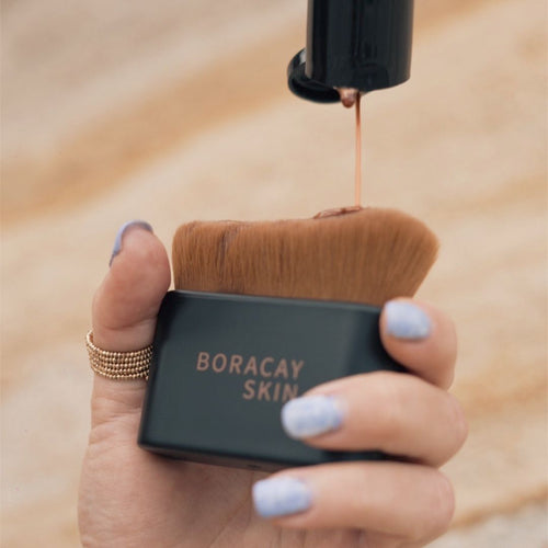 Boracay Skin kabuki brush being held by model with bronze shimmering body oil applied